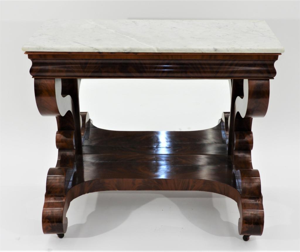 American Empire Flame Mahogany Veneer Pier Table: ,United States,19th Century Marble top over an ogee apron with scrolled supports and feet with mirrored back and bookmatched veneer. 40" x 18" top,40" x 21"x 35 1/2" tall,Veneer, wood From a Stoningto