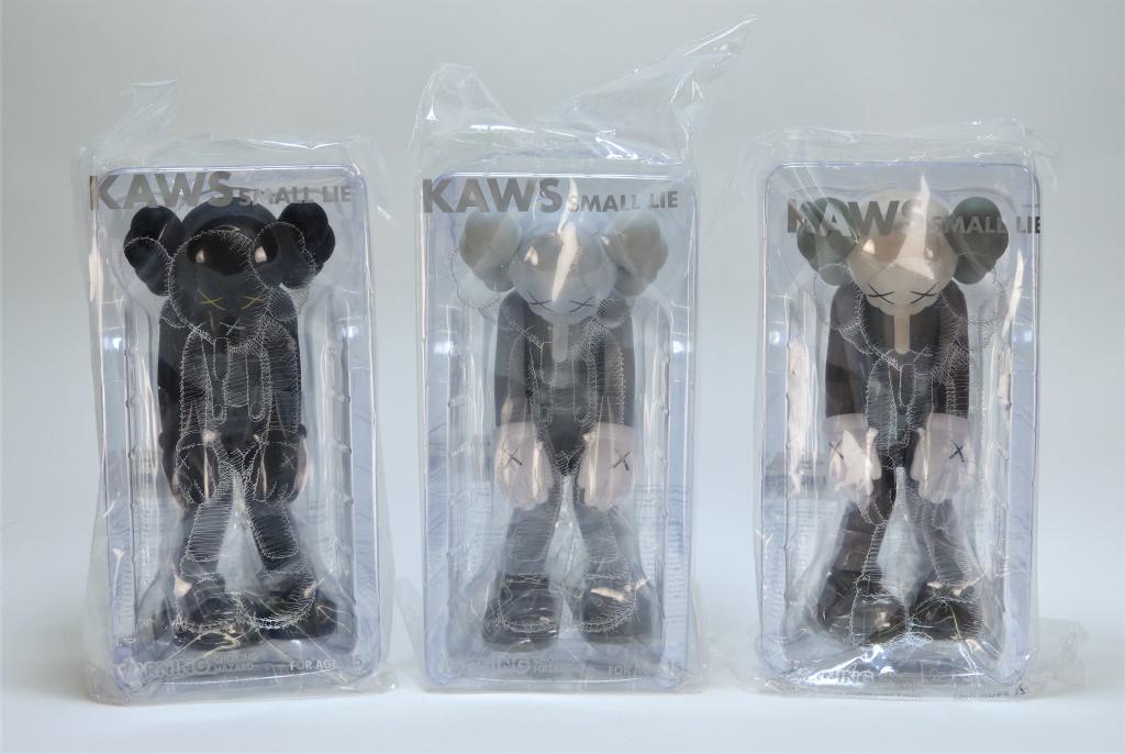3PC KAWS Small Lie Factory Sealed Sculpture Group: KAWS New Jersey, New York b.1974 Three works, Small Lie (Black, Brown, Grey), 2017, cast vinyl, limited edition. Each signed on underside of feet. Each 10 3/4" x 5" x 5",Cast vinyl From a private Rhod