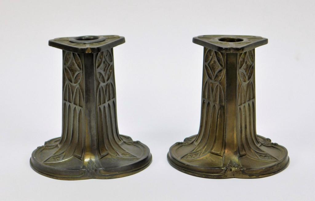 PR Pairpoint Art Deco Metal Candlesticks: Massachusetts 20th Century Triangular shaped candlesticks decorated with cathedral window patterns over body and flared base. 4 3/4" x 5 3/4" dia.,,Metal Marked "Pairpoint MFG CO" on bottom.,From the 