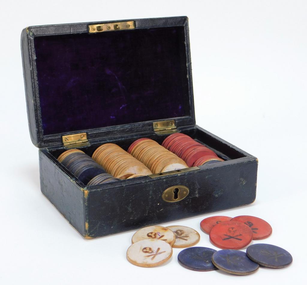 101Skull & Crossbones Poker Chip Set with Case: United States 20th Century Includes twenty six red chips, fifty white chips, and twenty five blue chips with skull and crossbones pyrography design in a purple velvet lined case. Chips 1 1/2" dia.,Box