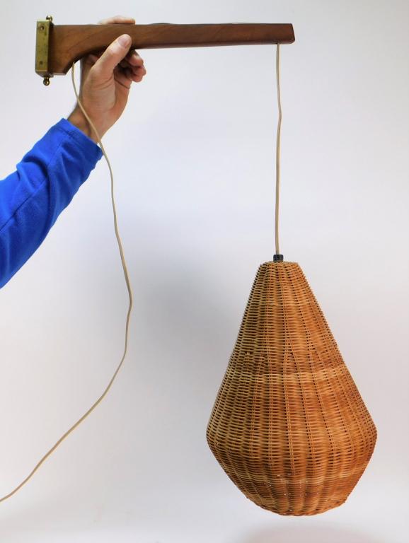 MCM Wicker Wall Pendant Light: United States 20th Century Teardrop shaped wicker basket shade supported by a wooden arm on mobile brass bracket. 26 1/2" x 14 1/4",Shade 8" dia.,Wood, brass ,From the collection of a Medfield, Massac