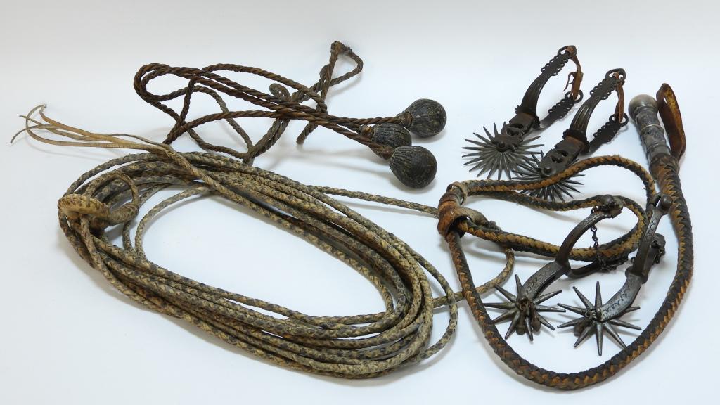 5PC Western Rodeo Lasso and Spur Group: United States 19th Century Includes a pair of spurs with decorative pierced sides, a pair of spurs with decorative engraving and hanging metal accessories, a bola, a lasso, and a whip with decorative 