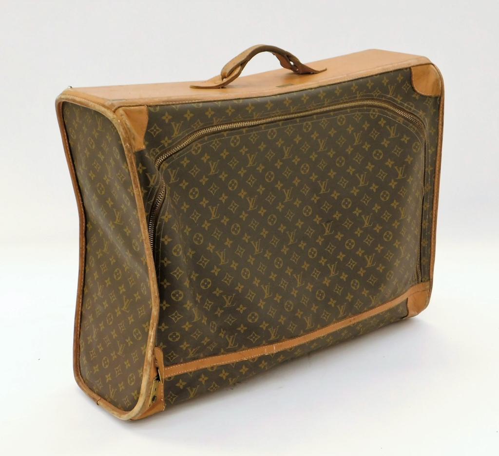 Louis Vuitton Monogram Suit Case: France,20th Century Large suitcase with iconic LV pattern and tanned leather piping details. Leather,21 1/2" t x 28 1/2" w x 9 1/2" d. Marked "Louis Vuitton" on interior, includes "Saks Fifth Avenue" 