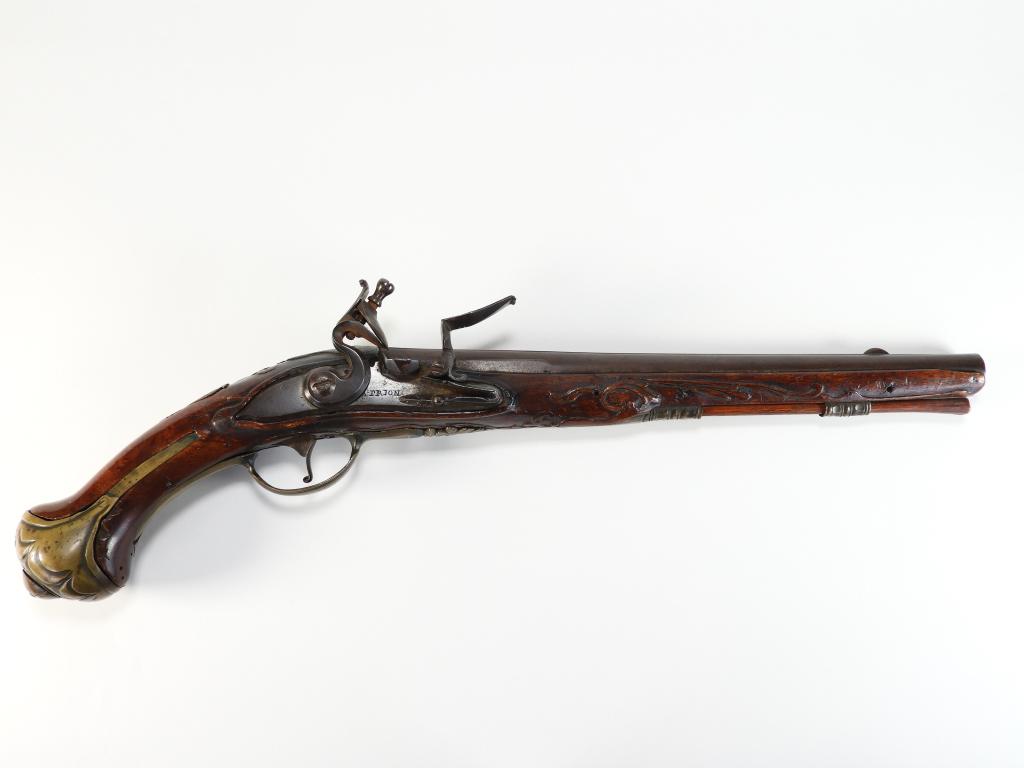 Antoine Prion Flintlock Holster Pistol: Belgium C. 1730s .56 bore, ornately carved walnut stock, brass fittings, lock marked "A. PRION" in front of the cock, barrel has a flat sighting plain and brass front sight, with a wooden ramrod. Barr