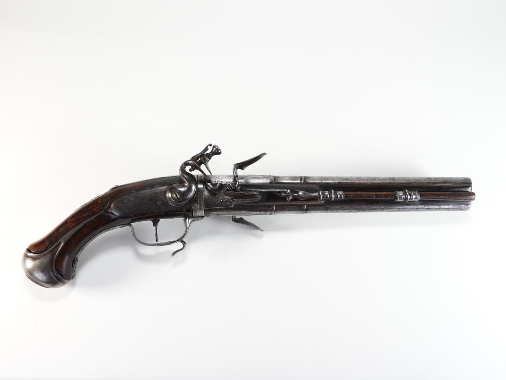 Revolving Two Barrel Flintlock Pistol: France C. mid-18th century .54 bore, walnut stock, iron fittings, lock plate engraved with foliate designs and an animal, barrel latch lever on the trigger guard, two revolving barrels, and a wooden r