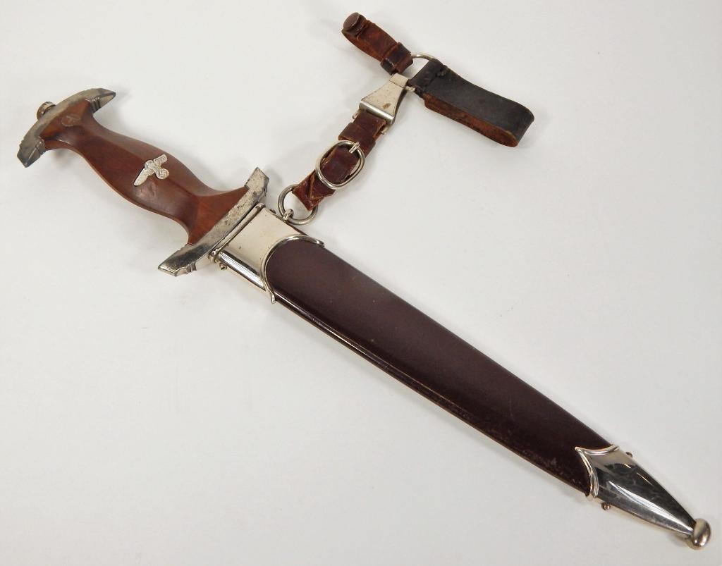WWII German SA Dagger, Scabbard, and Hanger: C. 1940 Wooden grip with inlaid "SA" disc near the top and an eagle, blade marked "Alles fur Deutschland" one side, and "RZM/M7/33/1940" on the other, with a brown-painted steel sheath, a chrome throa
