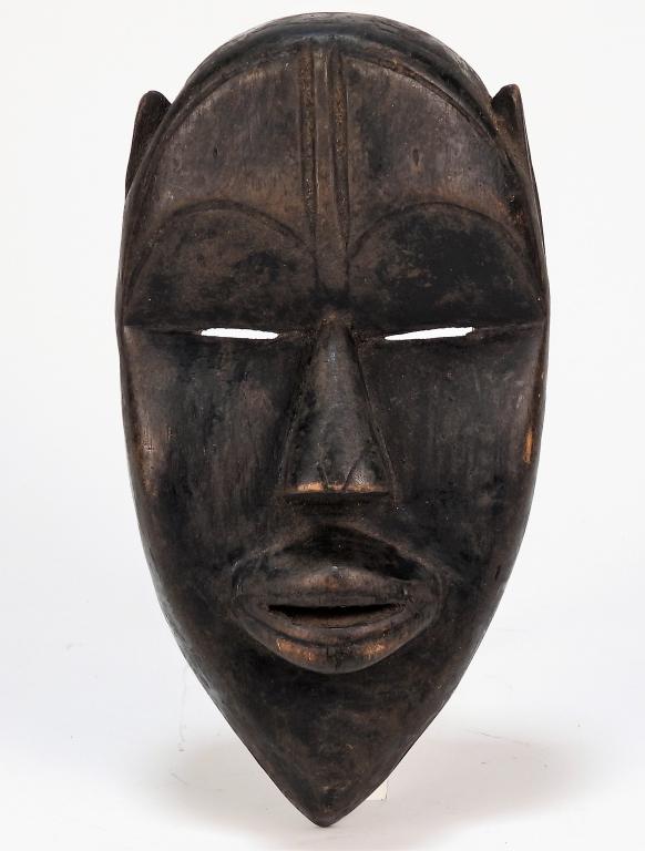 Attr. Mano Tribe Dan Style Carved Wood Mask: Africa, Early 20th Century Figural mask dyed black with arched eyebrows, small eyes, angular nose, and large protruding lips. Approx. 8 1/2" t x 4 1/4" w x 2 5/8" d. From the deaccessioned collection