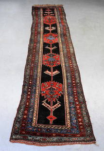 Northwest Persian Rug Runner: Middle East, Early 20th Century Blue, pink, yellow, red, and white geometric patterns over black field surrounded by geometric floral borders. Approx. 14' x 3' 5 1/2". From the collection of a Massach