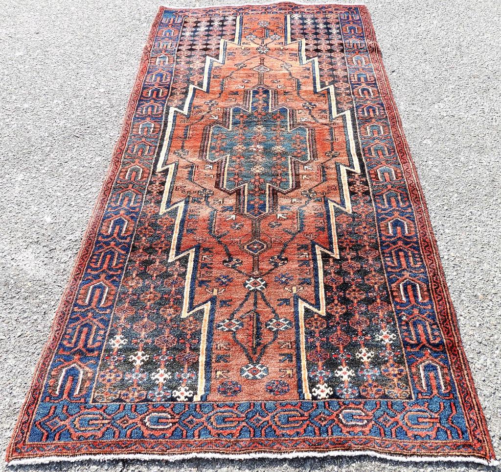 Persian Lauri Rug: ,Middle East,20th Century Navy blue, red, blue, orange, rust, and white geometric flloral over rust field surrounded by geometric floral field. Wool, Approx. 99" x 48". From the collection of a Massac