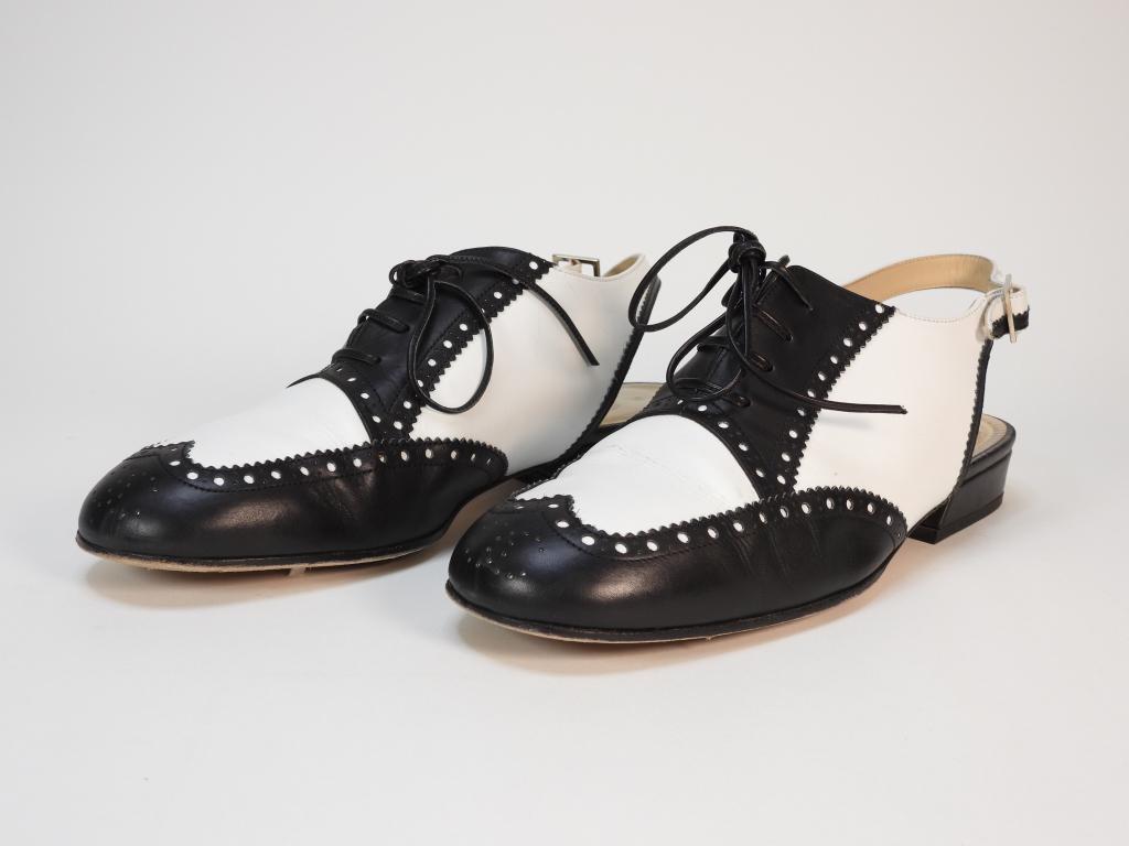 Chanel White & Black Leather Oxford Shoes size 9: White open back oxfords with adjustable heel strap, black toe caps and lace guards, and nude interior. Guaranteed authentic with original box and dust bag. Leather,European 40 Marked "Chanel Made in I