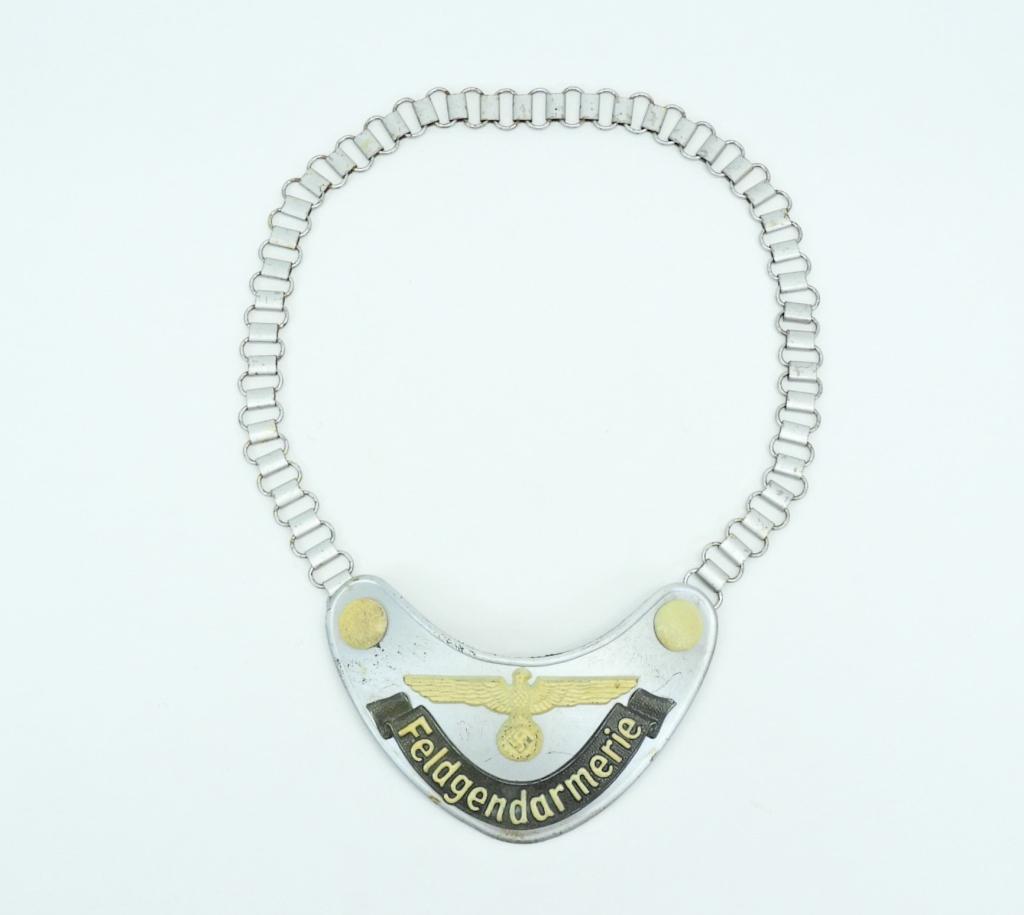 WWII German Feldgendarmerie Gorget and Chain: Germany,C. 1930s-40s Silver-painted gorget with pebbled buttons, an eagle and swastika, a green-painted banner marked "FELDGENDARMERIE", the back covered with field gray cloth, with a neck chain. Over