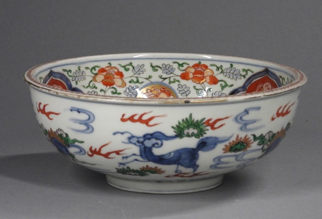Chinese Ming Qing Dynasty Wucai Porcelain Bowl: China,Ming-Qing Dynasty White porcelain with blue underpainted foo beast center surrounded by polychromatic flowers and foo lion cartouches. Porcelain,3 1/4" x 8 1/2" dia.. Bears six character Ming ma