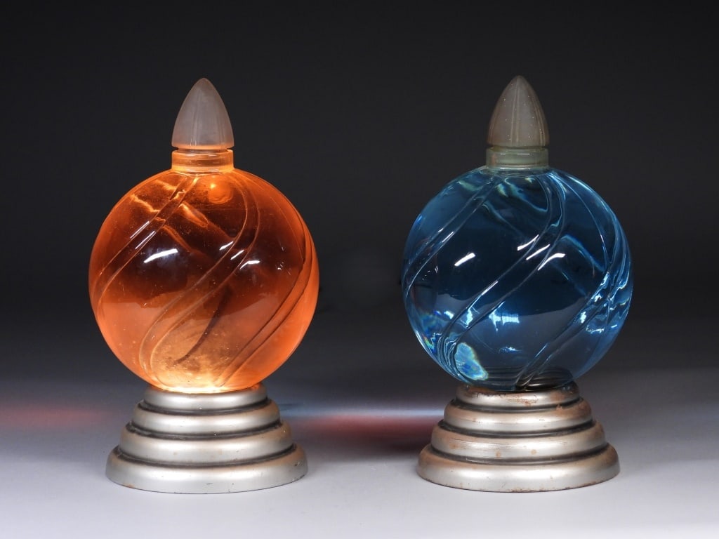 PR Art Deco Apothecary Light Up Display Jars: United States,20th Century Pair of globe shaped swirled glass bottles over light up stepped metal bases. Glass, metal,Each approx. 14 1/2" x 8" dia.. From the collection of a Cranston, Rhode Island es