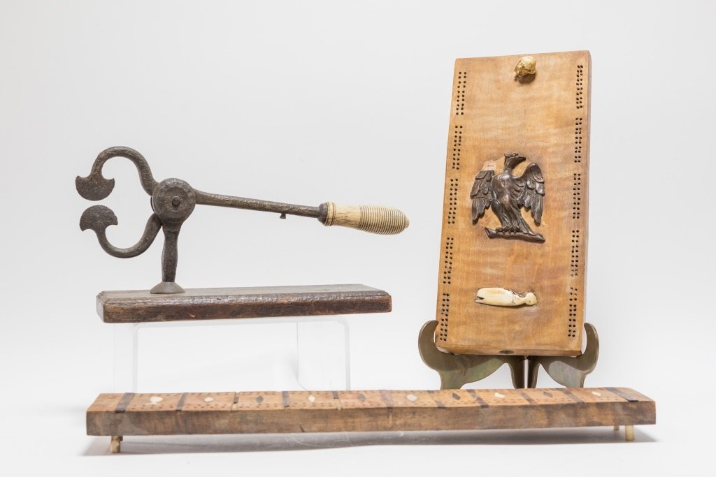 3 Whale Bone Scrimshaw Cribbage Sugar Cube Cutter: UNITED STATES, 19TH CENTURY Three American whale bone scrimshaw items. The lot consists of a cribbage board with center carved wood eagle accented by carved whale bone whale and figural head of a man,