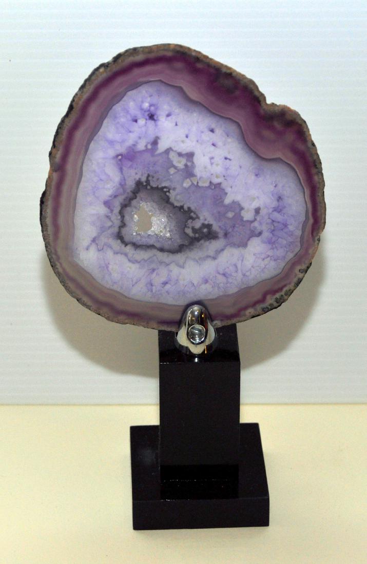 Sliced agate geode on stand: Sliced agate specimen with druzy crystalling structure in the middle - crystals are brilliant sparkling and the specimen is set onto black stand -about 8 1/2 inches high.