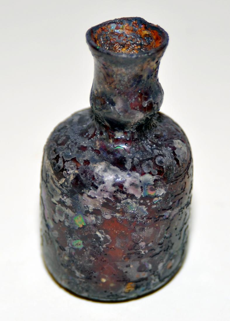 Roman glass bottle purple brown color: Roman glass bottle - shows some silvering from being in sand - unusual brown tone -probably with silver iridescent color - most likely found in trans Jordan area. About 2 1/2 inches- 3 inches