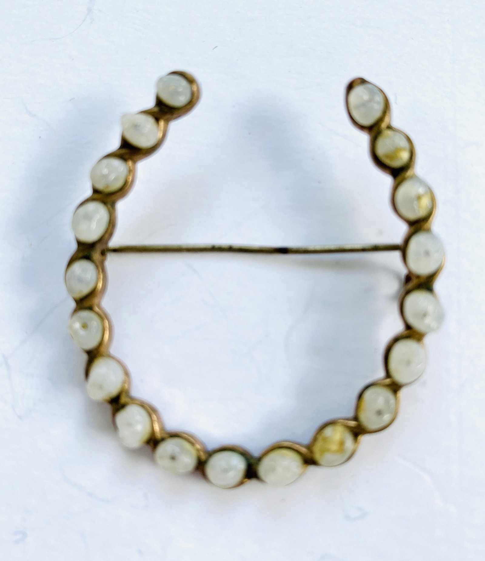 Vintage horseshoe pin moonstones: Vintage horseshoe pin encrusted with what appears to be moonstones. Pin is about 1 1/2 inches in diameter and is very unique.