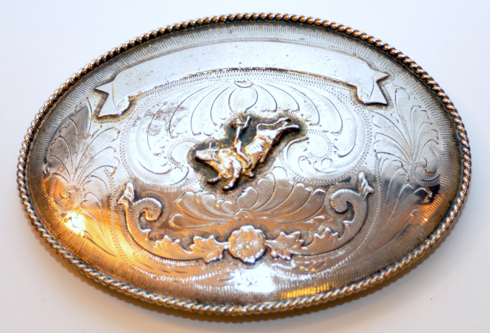 Rodeo belt buckle cowboy large: Large oval rodeo belt buckle with bucking bronco on front - white and yellow gold color - buckle not inscribed -about 6 1/2 x 5 inches