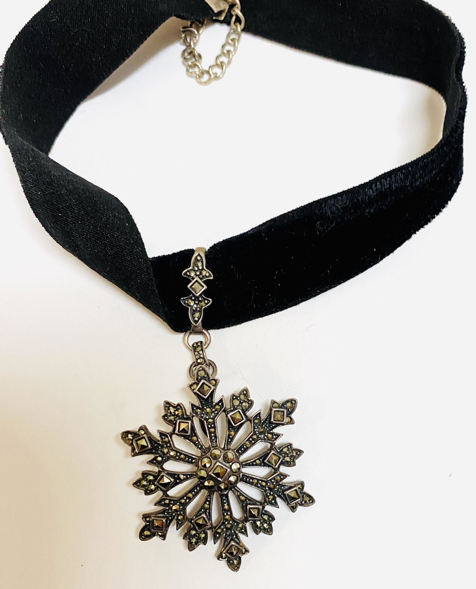 Marcasite snowflake sterling pendant on velvet: Sterling snowflake marcasite pendant beautifully designed on velvet ribbon . About 1 1/2 across on pendant and 17-18 inches long. The necklace could easily be made longer with design of clasp .