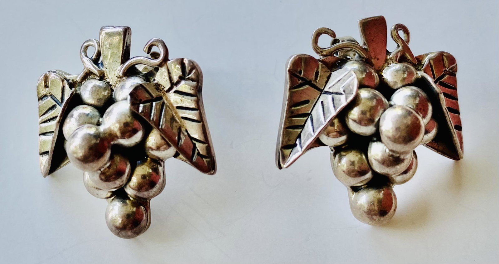 Sterling grape/earrings pierced: Sterling silver marked grape/leaf earrings about size of dime each marked 925 Mexico and numbered on back.