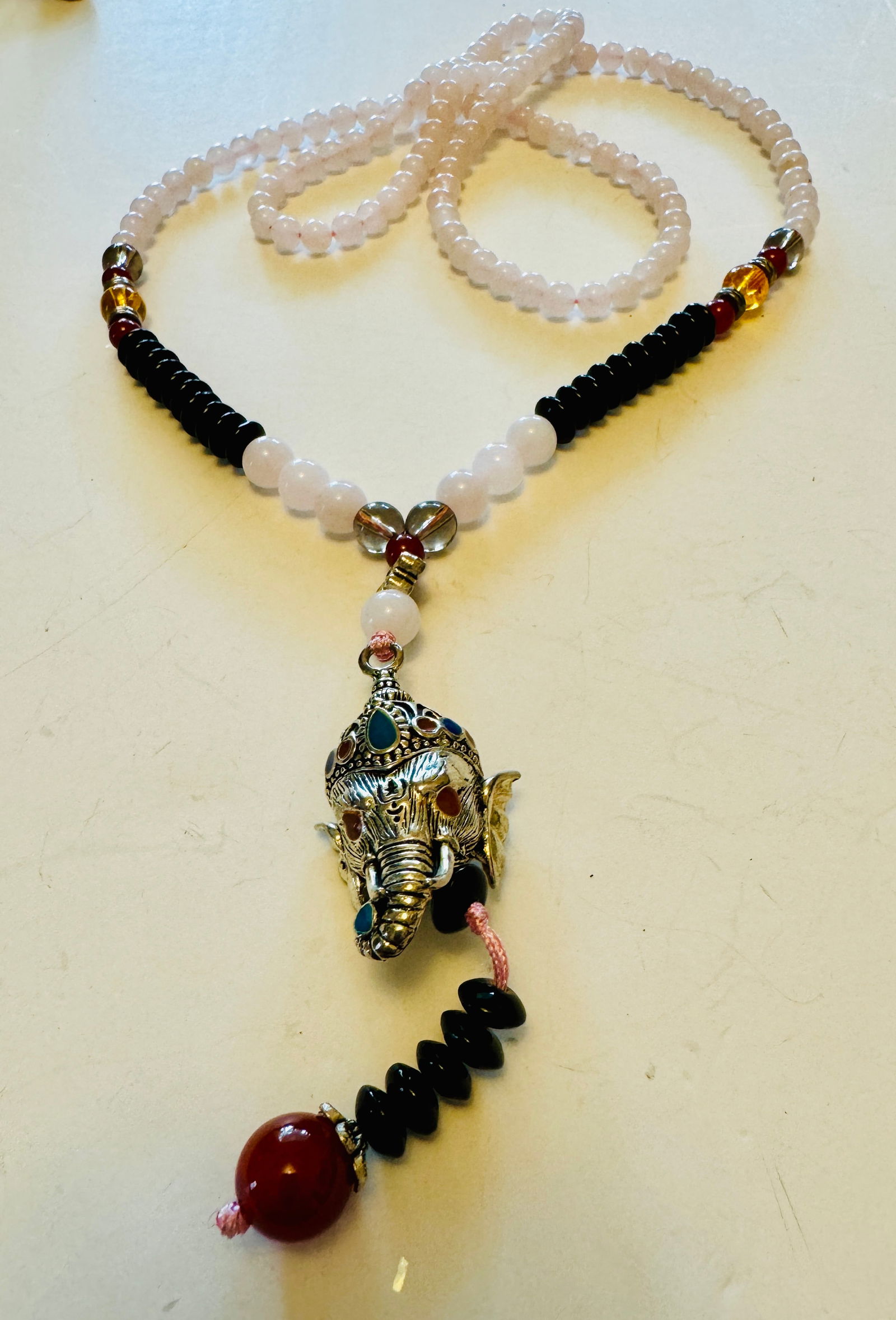 Rose quartz black onyx neckalce /elephant pendant: Rose quartz beads with black accent beads most likely onyx.. And elephant head ganesh with stone eyes.. Custom and about 26-28 inches long.