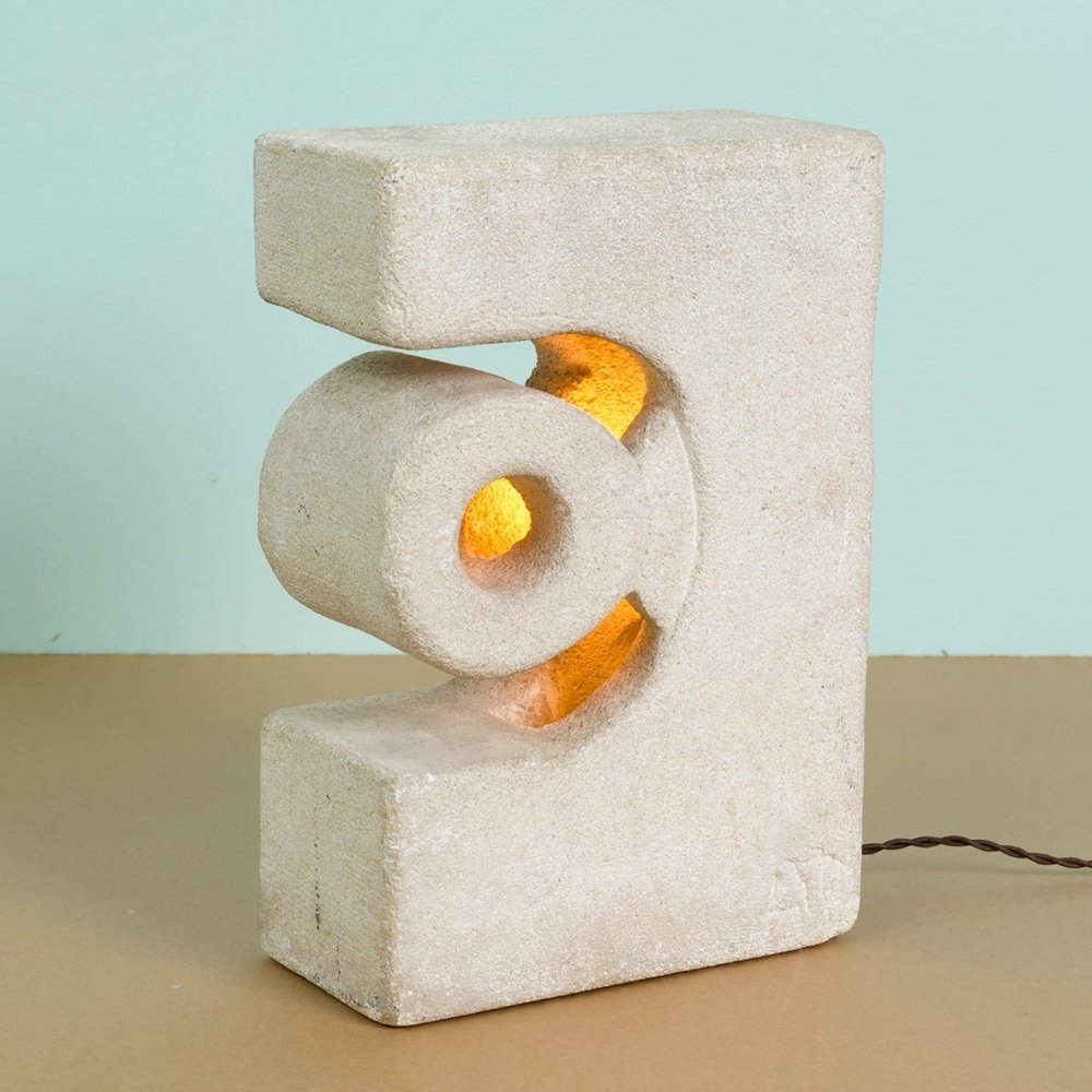 Cement Table Lamp: A contemporary signed cement table lamp. This rectangular prism shaped table lamp is comprised of cement and features a semi circle cut-out facing to the left and embellished with a torus, both stemmi