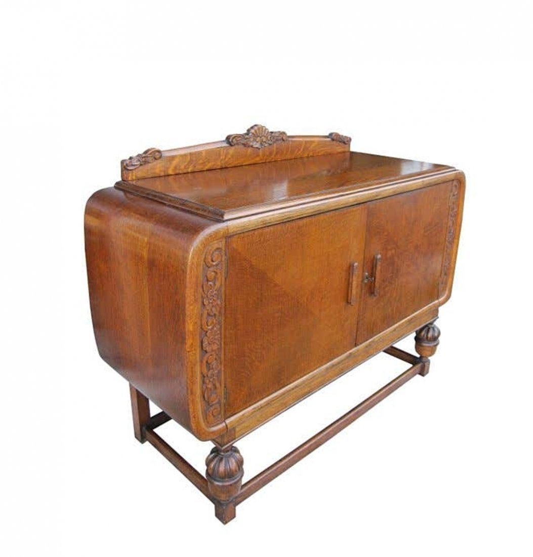 Art Deco Sideboard, England, circa 1920s: Beautiful 1920s deco English cabinet made in solid wood with beautiful carved motifs. The cabinet has three concealed doors and a cabinet with a shelf for storage. The cabinet comes with the original 