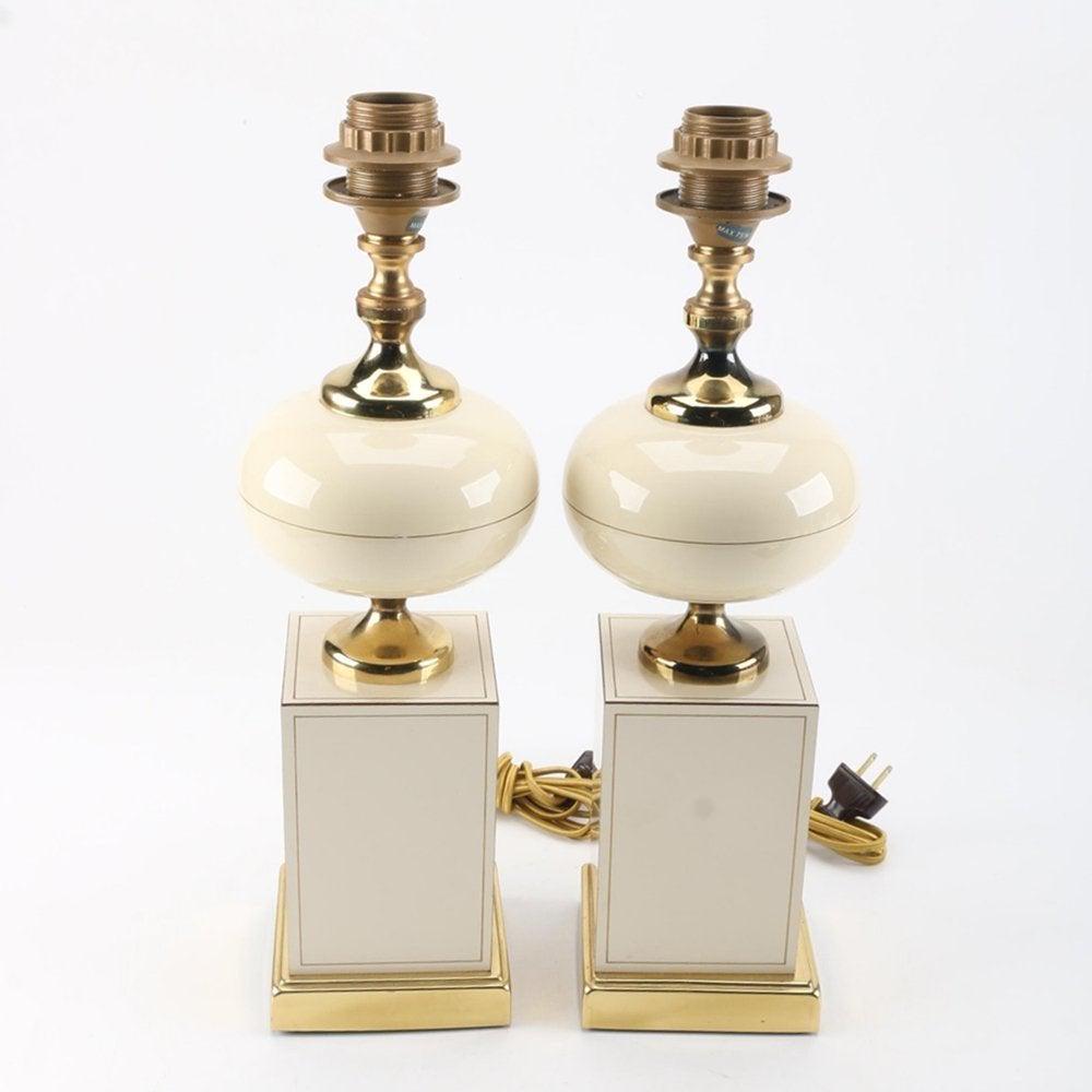 Ceramic and Brass Table Lamps, Circa 1960: A pair of vintage table lamps with brass accents. This selection includes a matching pair of table lamps with gold toned sockets and a curvaceous brass neck, font cap, and rectangular base. The bipart