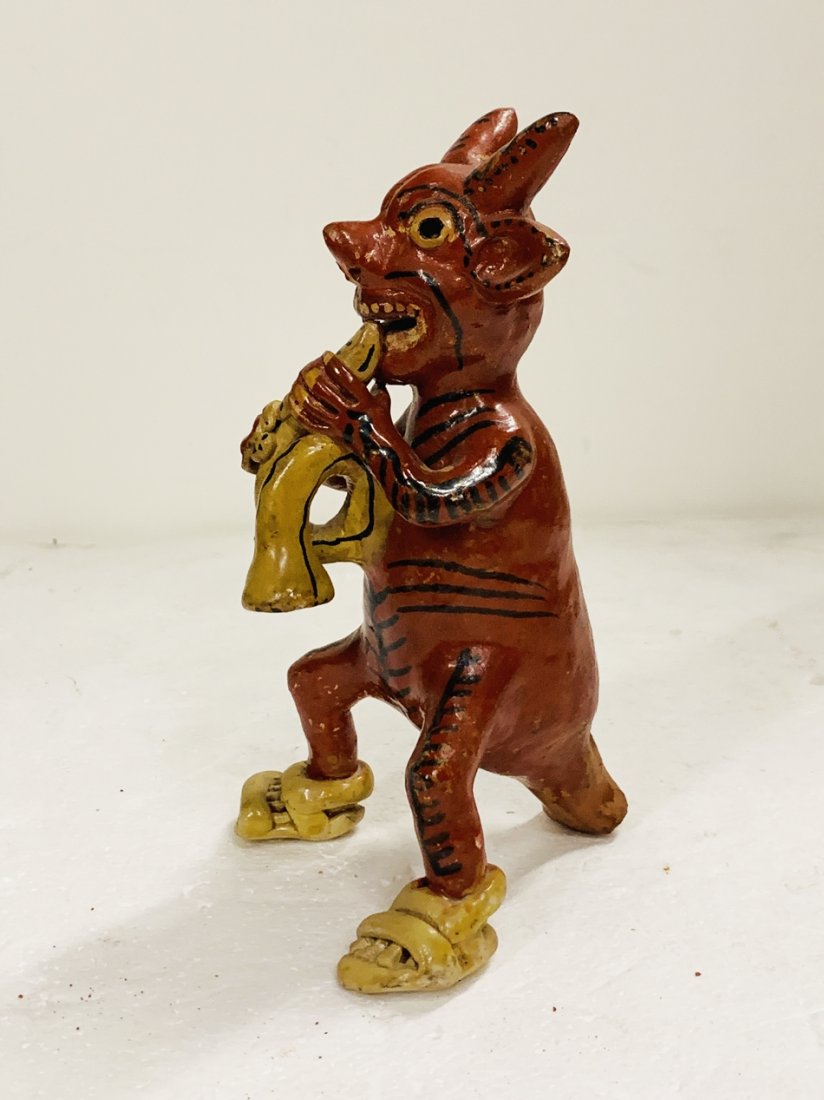 Diablito Clay Sculpture, Ocumicho Style: Ocumicho style pottery sculpture of a diablito sitting on his tail, wearing Guaraches and either eating someting or playing an instrument. The piece came with other ocumicho pieces but this is not sig
