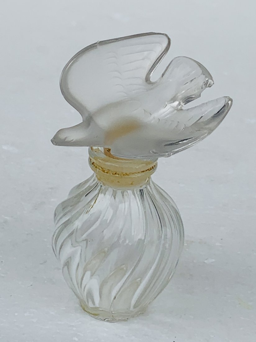 Perfume Bottle with Stopper by Lalique: Lalique perfume bottle. Stopper features a frosted, single dove in flight with wings extended. Bottle features a twisted swirl glass design. Measurements: 3.5 inches high x 2 inches wide Signed at the
