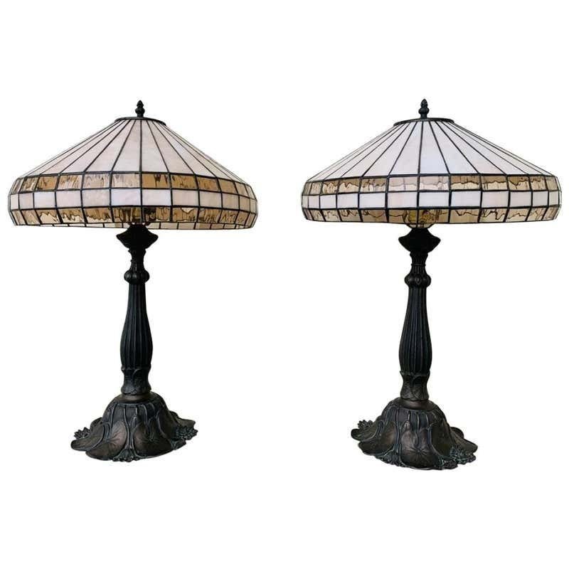 Tiffany Style Table Lamps in Bronze & Stained Glass: Beautiful pair of bronze table lamps paired with a stained glass and bronze shades. The lamps have beautiful sculpted bases with calla Lilly design.The lamps are in excellent condition and ready to be