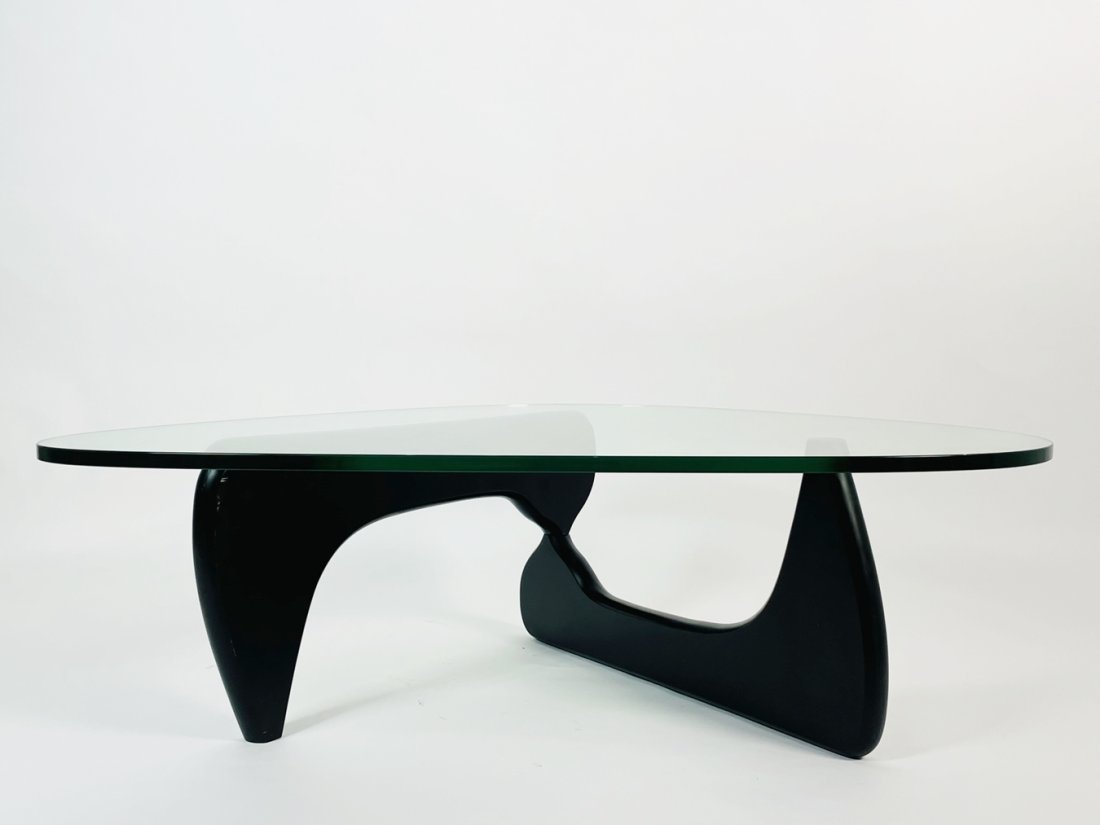 Wood and Glass coffee table in the style of Isamu Noguchi: The brilliantly simple design consists of only three elements, the glass top and two interlocking wood base pieces. The table is an extraordinary harmony of form and function. Unsigned. Measurements: 