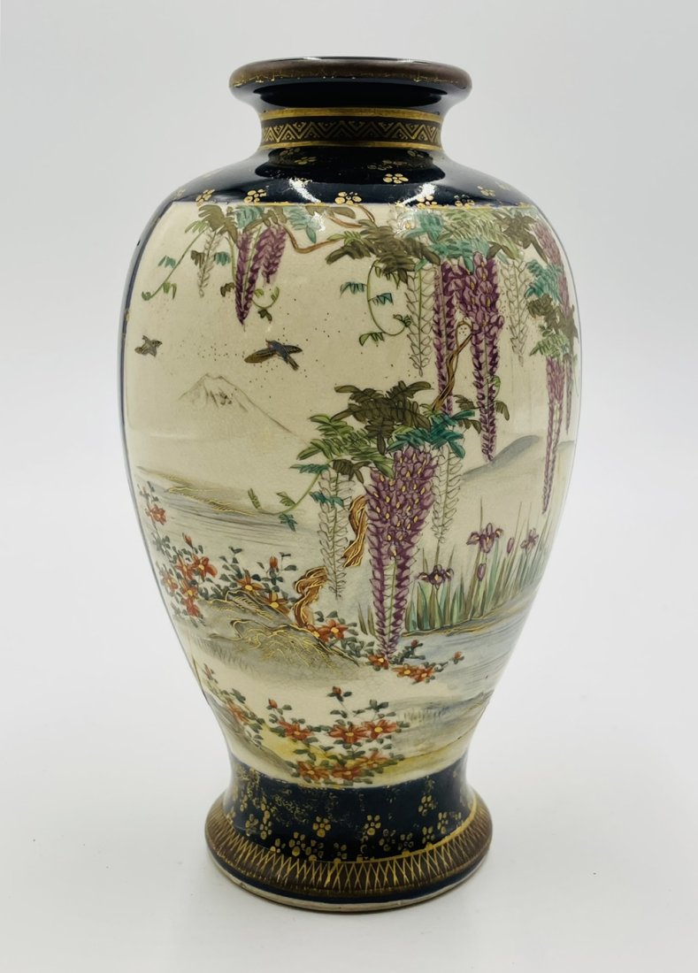 Japanese Satsuma Vase: This magnificent gold gilt with a cobalt background vase is decorated with geishas gathered by a lake beneath a wisteria tree on one sides, and more geishas underneath a blossoming tree on the other s