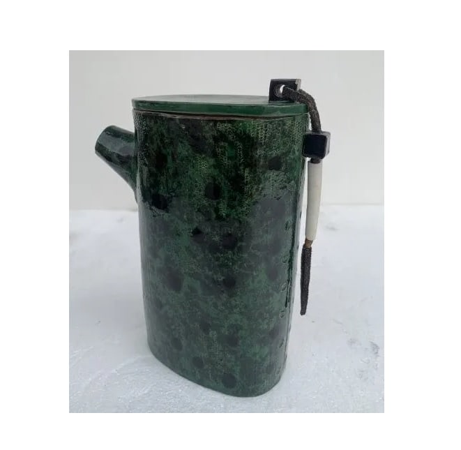 Textured Ceramic Vessel by Stella Vognar: Beautiful ceramic vessel made in 1990 by Los Angeles based artist Stella Vognar. The piece has a beautiful deep green finish, the lid is attached with leather and copper wire. The piece is signed and 