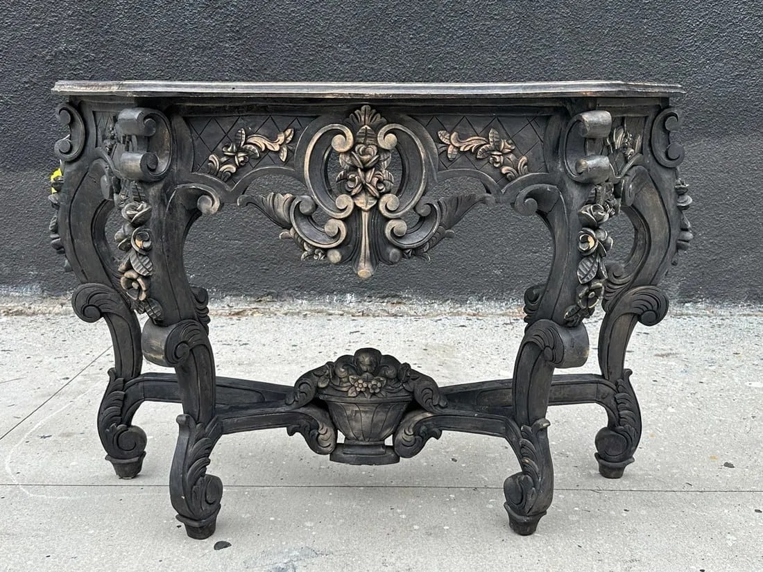 Hand Carved Console Table in a Black Finish: Hand carved console table with a black finish. Measurements: 50 inches wide x 15.25 inches deep x 32.75 inches high. All items are sold as is. The auction house does not warrant authenticity on any sp