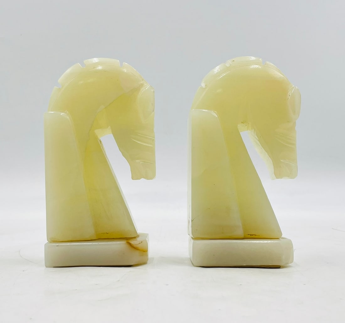 Pair of Vintage Hand-Carved Onyx Horse Head Bookends in the Style of Chess Knights: A charming pair of vintage bookends finely hand-carved from creamy pale onyx, each shaped in the form of a stylized chess knight. These sculptural pieces feature soft translucence with natural veining