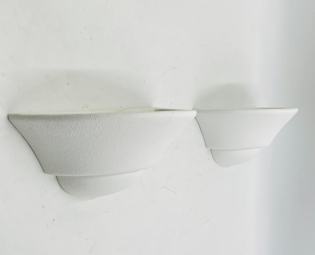 Pair of Modern White Ceramic Wall Sconces: Sleek and minimal pair of white ceramic wall sconces with a textured matte finish. These contemporary light fixtures feature a flared half-dome shape and upward-facing design for a soft, ambient glow.