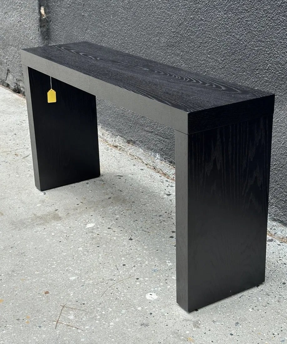 Black Console Table With a Ceruzed Oak Finish: Black console table with a ceruzed oak finish. Measurements: 58 inches wide x 15 inches deep x 31 inches high. All items are sold as is. The auction house does not warrant authenticity on any specific