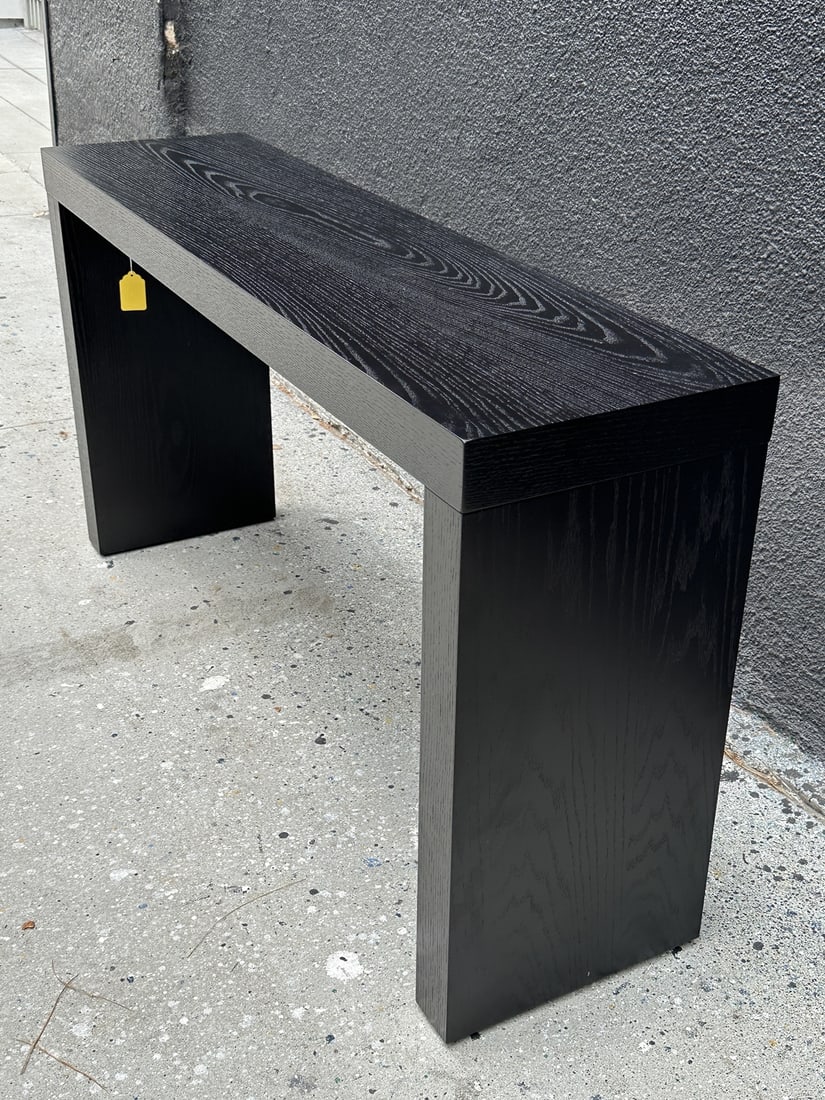 Black Console Table With a Ceruzed Oak Finish: Black console table with a ceruzed oak finish. Measurements: 58 inches wide x 15 inches deep x 31 inches high. All items are sold as is. The auction house does not warrant authenticity on any specific