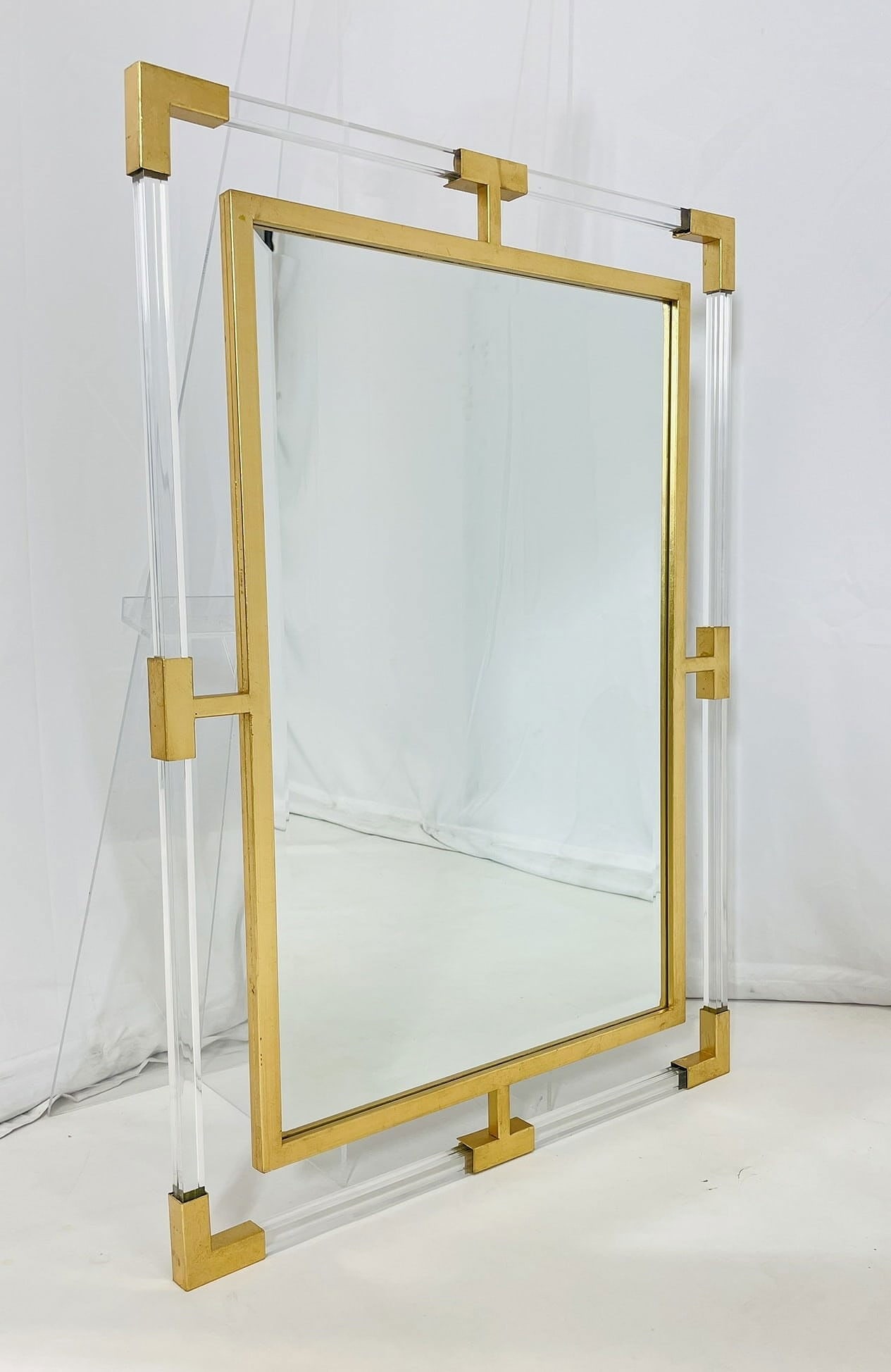 Lucite and Brass Tone Wall Mirror by Uttermost: Lucite and brass tone wall mirror by uttermost. Measurements: 37.25 inches high x 27.50 inches wide x 1 inch deep. All items are sold as is. The auction house does not warrant authenticity on any sp