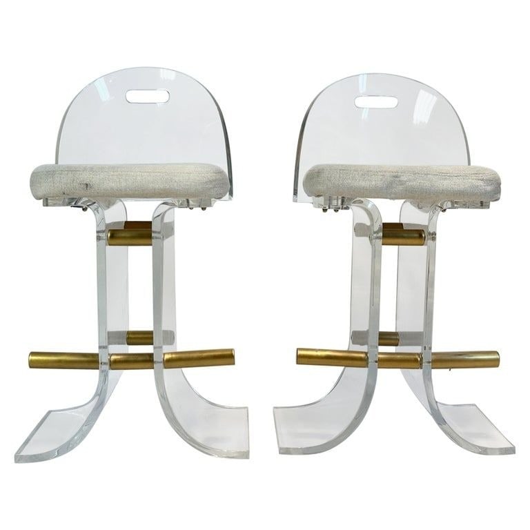 Lucite & Brass Counter Stools after Charles Hollis Jones: Introducing our exquisite Pair of Lucite & Brass Tone Counter Stools by Hill Manufacturing, crafted in the USA during the stylish 1970s. Each stool showcases a sleek backrest adorned with striking br