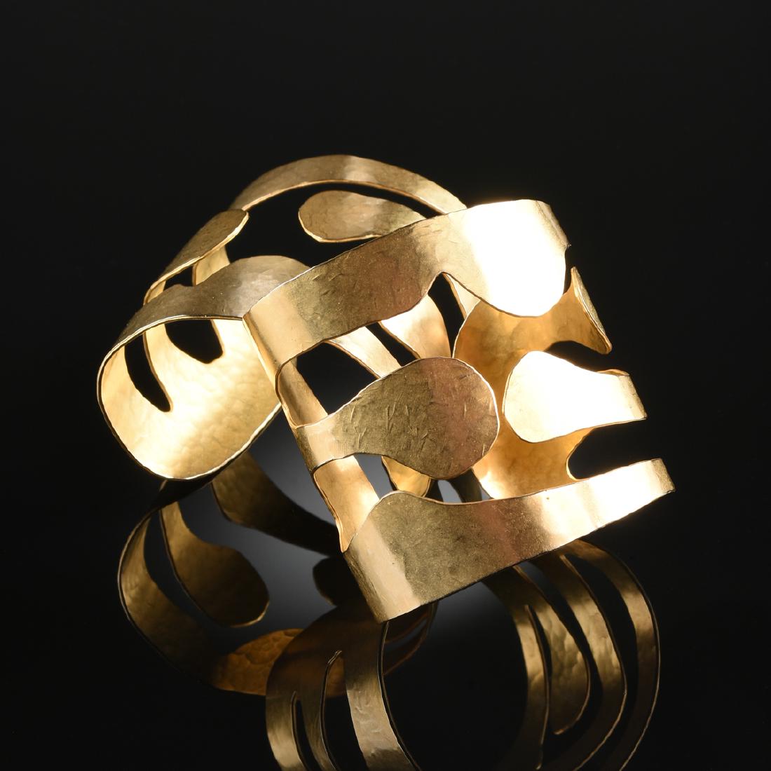 A PAIR OF 24K YELLOW GOLD PLATED ROBERT LEE MORRIS: A PAIR OF 24K YELLOW GOLD PLATED ROBERT LEE MORRIS LADY'S WRIST CUFFS, the hand hammered fused gold plated metal cuff of abstracted cut out rib pattern, adjustable size. Height: 2 1/4" Width: 2 1/2" D