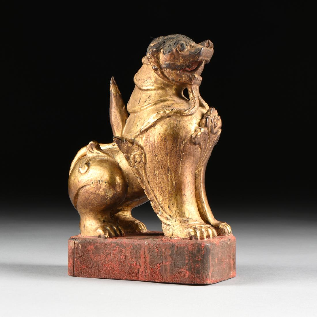 A BURMESE GILTWOOD CHINTHE PAGODA GUARDIAN LION,: A BURMESE GILTWOOD CHINTHE PAGODA GUARDIAN LION, MAYANMAR, KONBAUNG DYNASTY (1752-1885) PERIOD, the seated lion with armored neck, a long bisected twisted beard issuing from an open mouth, above a flo