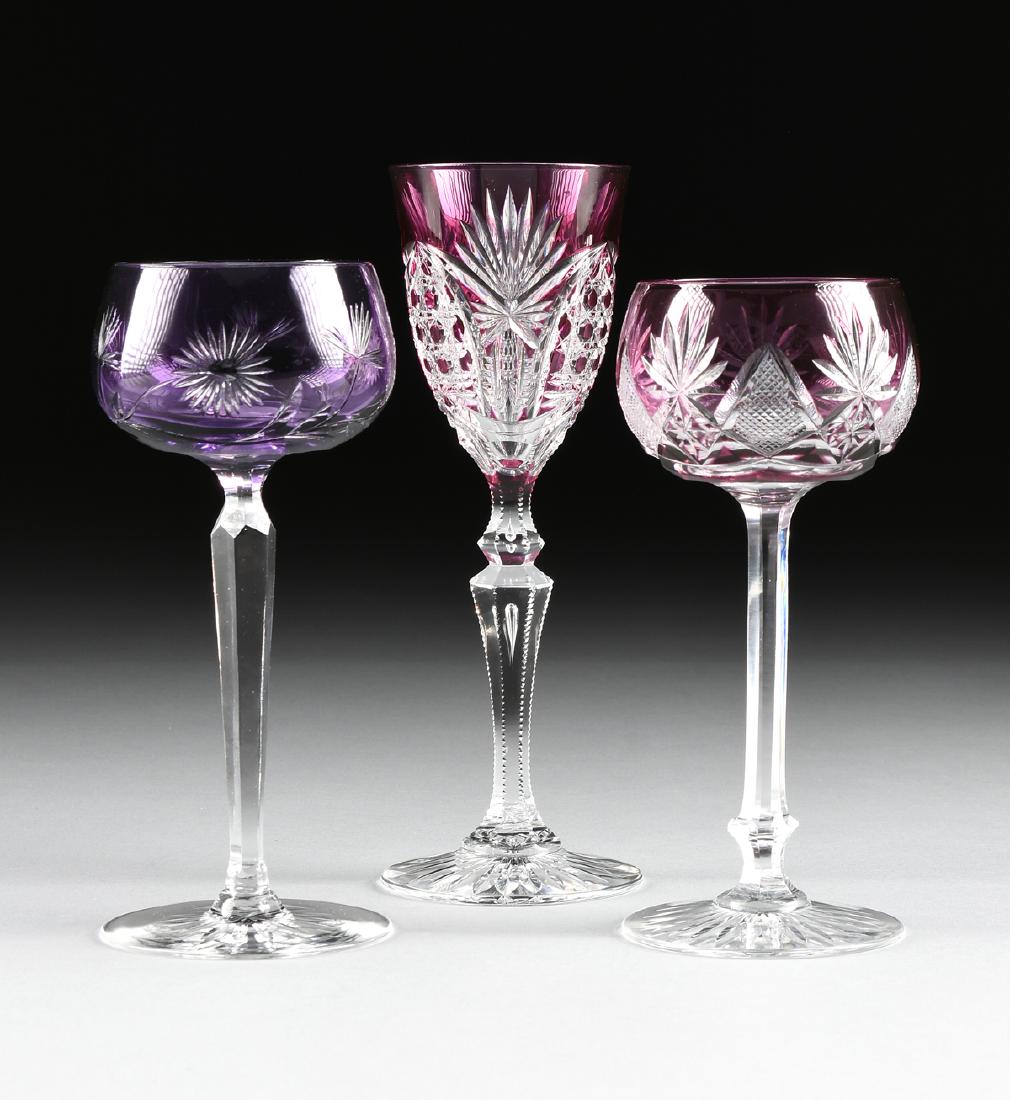 A GROUP OF THREE CONTINENTAL CASED AND CUT AMETHYST: A GROUP OF THREE CONTINENTAL CASED AND CUT AMETHYST WINE GLASSES, CIRCA 1900, comprising a Josephinenhutte deep amethyst Rhine wine glass, the bowl cut with stylized floral and leafing stem decoration
