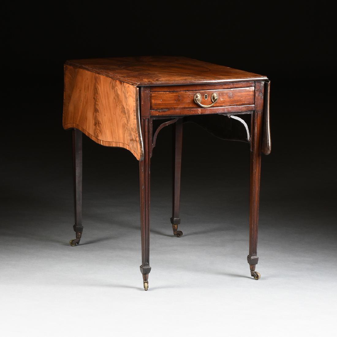 A FEDERAL INLAID MAHOGANY PEMBROKE TABLE, EARLY 19TH CE: the serpentine drop leaf top centering an oval medallion within sunburst rays, over a single end drawer, opposed by a faux drawer, raised on tapered, square legs, ending in square feet on casters, hei