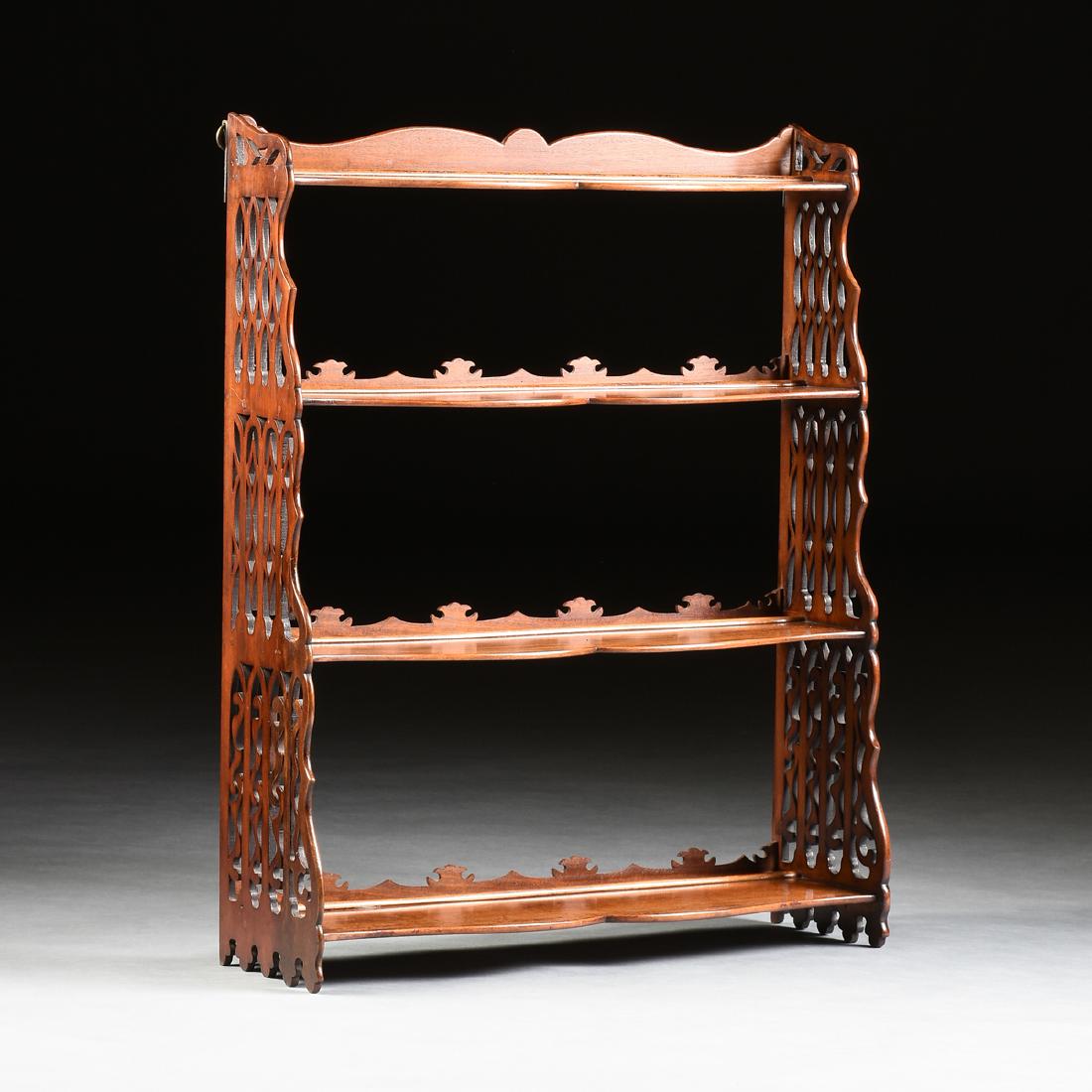 A VICTORIAN GOTHIC REVIVAL FRETWORK HANGING MAHOGANY: A VICTORIAN GOTHIC REVIVAL FRETWORK HANGING MAHOGANY ÉTAGÈRE , MID/LATE 19TH CENTURY, the serpentine back joined by pierced fretwork sides, joining four, cascading, serpentine plate or "whatnot" she