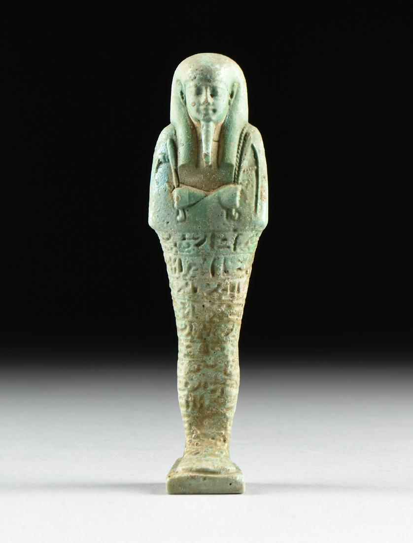 AN ANCIENT EGYPTIAN STYLE FAIENCE USHABTI, LATE PERIOD,: AN ANCIENT EGYPTIAN STYLE FAIENCE USHABTI, LATE PERIOD, 26TH DYNASTY, 664-525 BC, the green and blue color glazed funerary figure of mummiform with wrapped vestment around crossed arms with emerging c