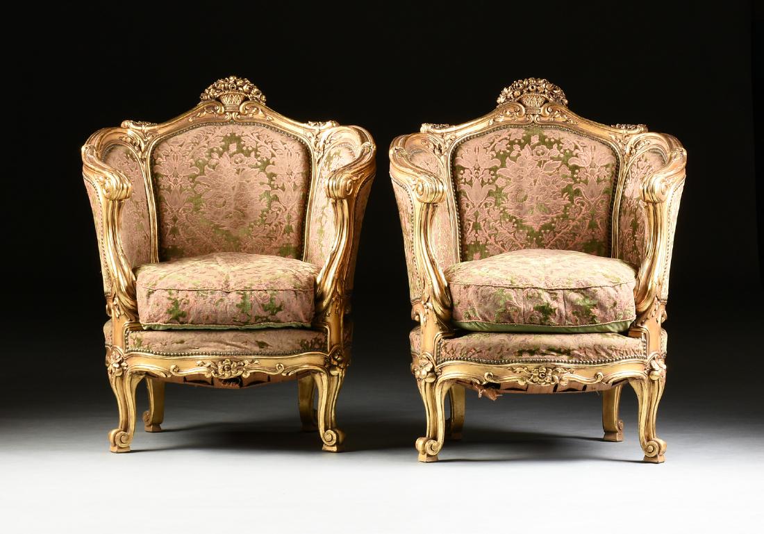 A PAIR OF ROCOCO REVIVAL PARCEL GILT CARVED WOOD: A PAIR OF ROCOCO REVIVAL PARCEL GILT CARVED WOOD BERGÈRES EN GONDOLE, LATE 19TH/EARLY 20TH CENTURY, each with an arched crest rail of paired curling tipped reeds flanking a reticulated flower filled 