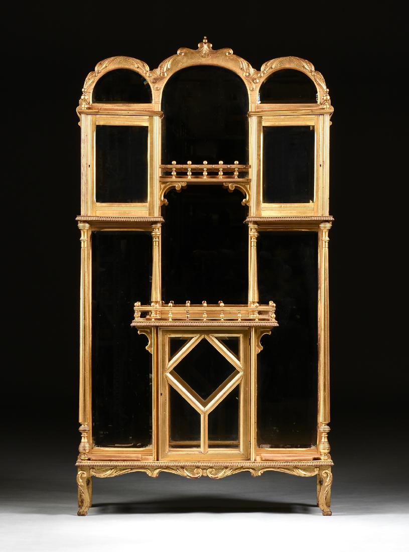 AN AESTHETIC MOVEMENT GILT AND CARVED WOOD MIRROR: AN AESTHETIC MOVEMENT GILT AND CARVED WOOD MIRROR BACKED DISPLAY CABINET, CIRCA 1875, the triple arched cornice with stylized scrolling foliate trim, enclosing one long beveled mirror back plate withi