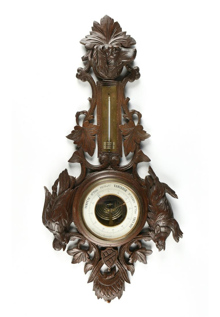 A FRENCH BLACK FOREST STYLE CARVED WOOD BAROMETER: A FRENCH BLACK FOREST STYLE CARVED WOOD BAROMETER ANEROID, EARLY 20TH CENTURY, with a carved portrait dog bust above a celsius thermometer and a white ring form barometer with weather conditions in Fr